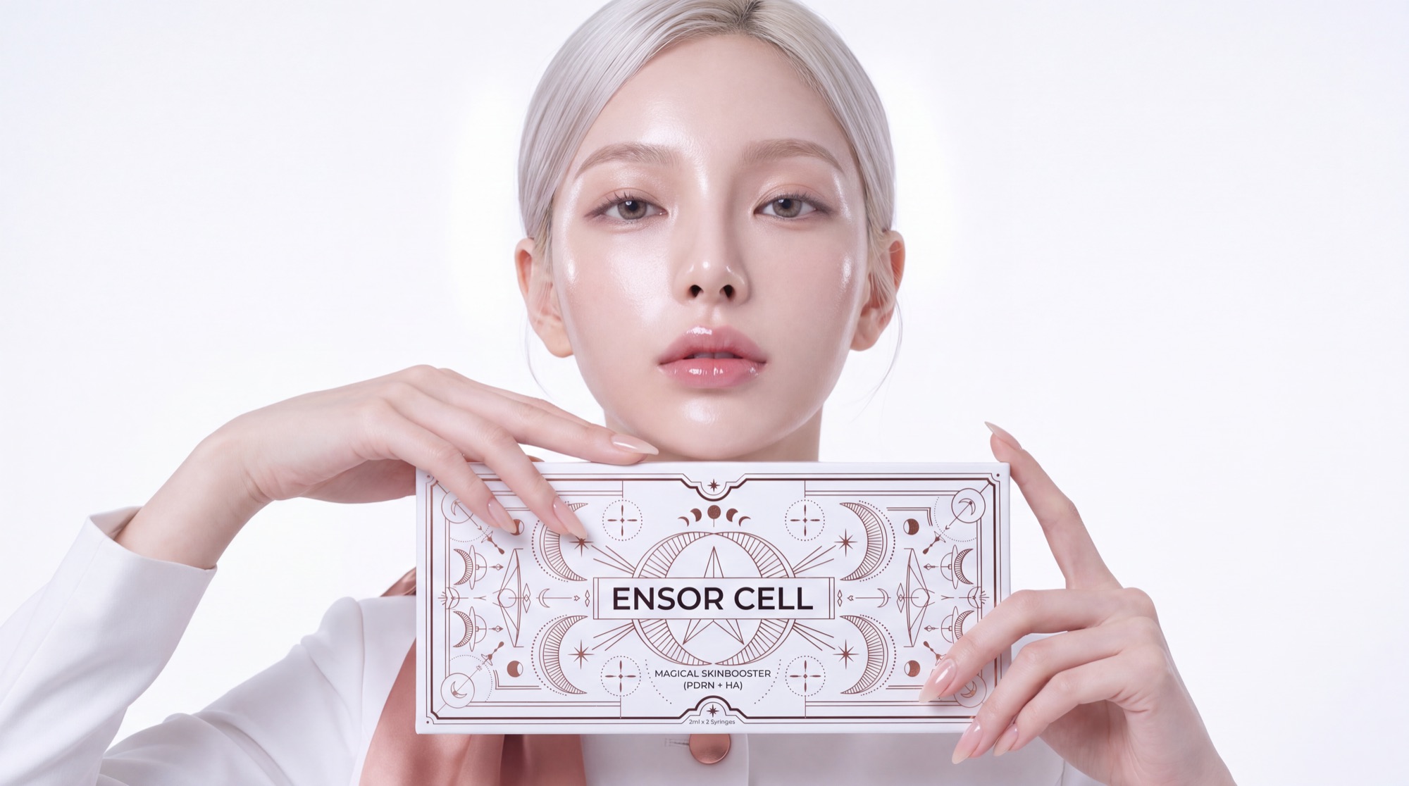 Model in a white high-collar jacket holding the ENSOR CELL Magical Skinbooster box at her collarbone, white studio